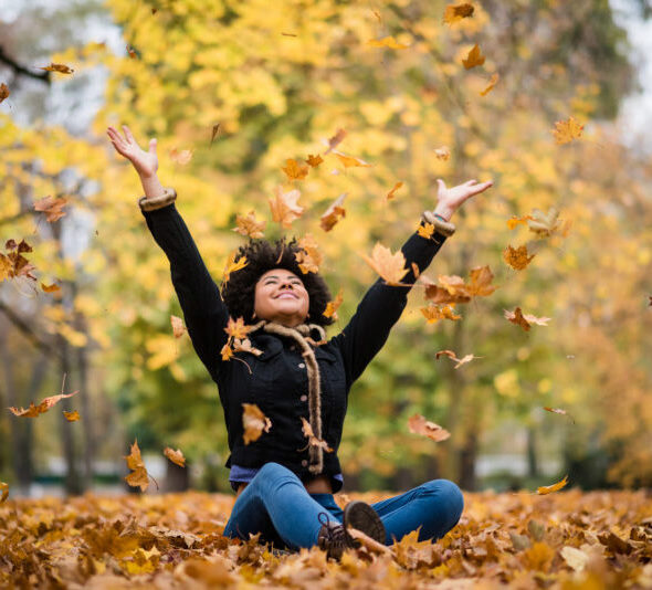 Happy woman in autumn park drop up leaves